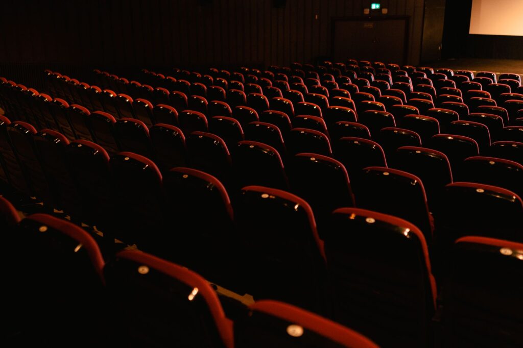 Rows of empty red seats in a darkened movie theater, awaiting audience.